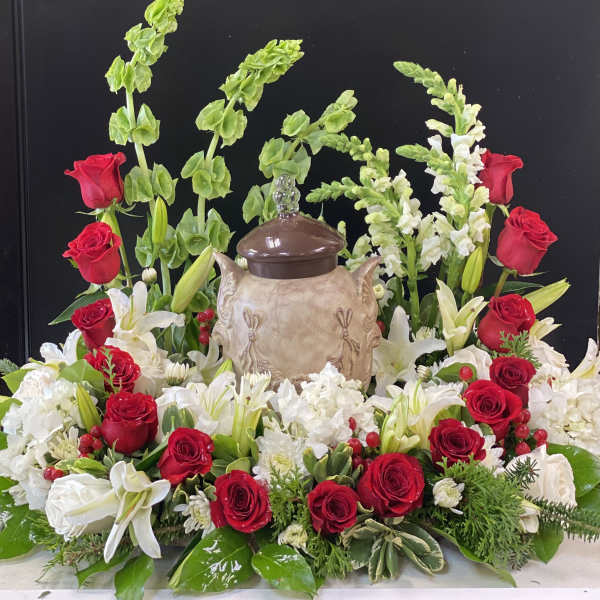 Red roses and white lilies arranged around a decorative urn on a black background.