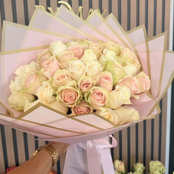 Bouquet of pale pink and cream roses wrapped in pink paper