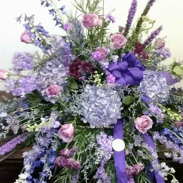 Large purple and pink floral spray with ribbon on a table
