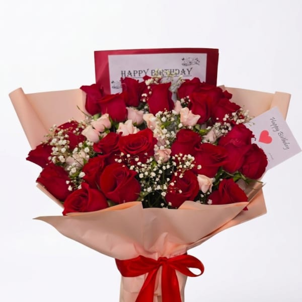 Bouquet of red roses and pale pink flowers wrapped in peach paper
