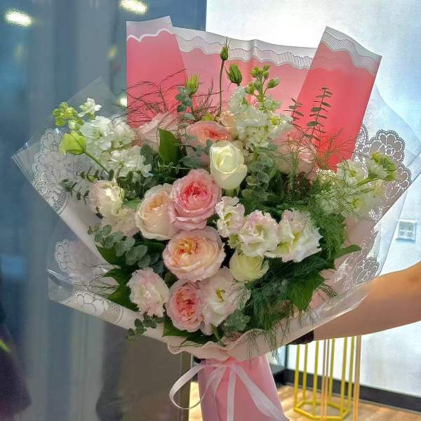 Pink and white bouquet with roses and ruffled blooms wrapped in pink paper