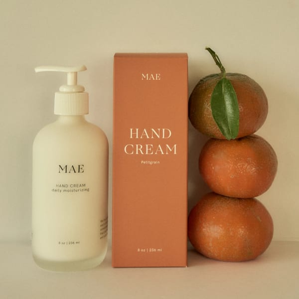 Hand cream bottle and box beside stacked oranges