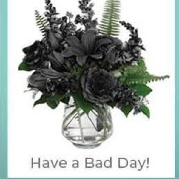 Dark floral arrangement in a clear glass vase with the text 'Have a Bad Day!'
