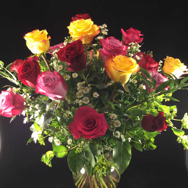 Mixed roses in a clear glass vase with small white filler flowers