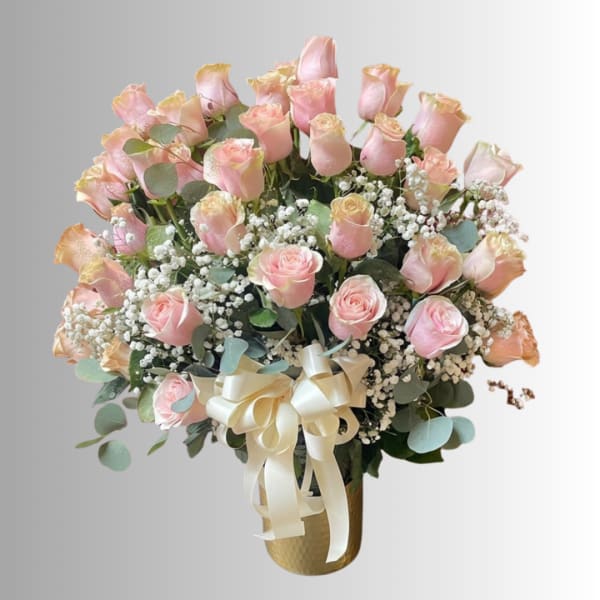 Bouquet of pale pink roses with baby's breath in a gold vase and ribbon