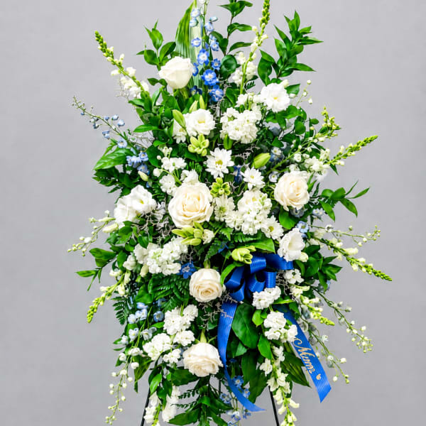 Tall white and blue floral standing spray on a black easel