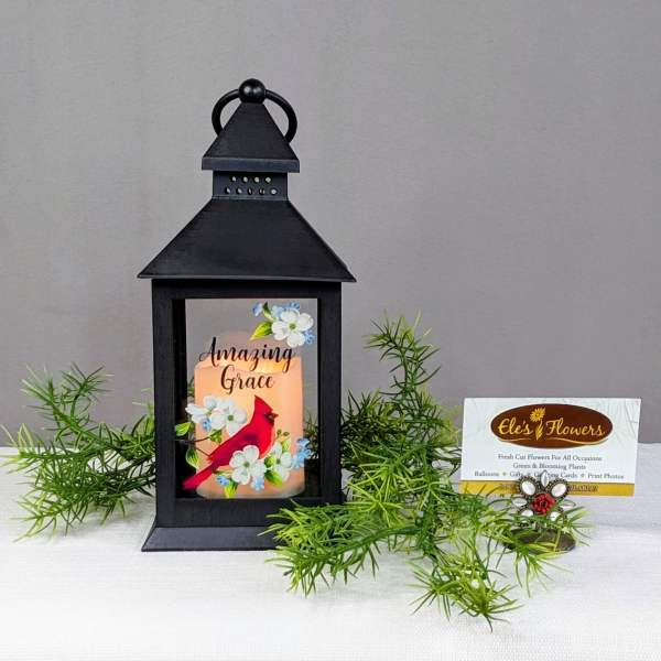 Black lantern with a lit candle and floral cardinal design