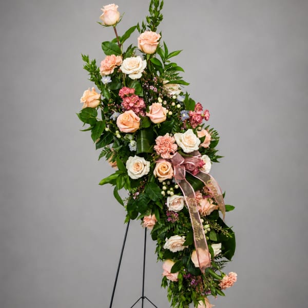 Tall floral spray with peach and white roses on a black stand