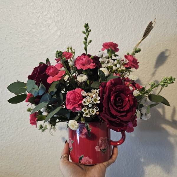 Pink and burgundy flower arrangement in a red mug
