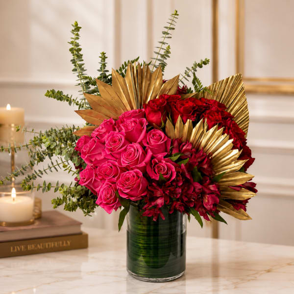 Pink and red roses arranged in a glass vase with gold leaf accents