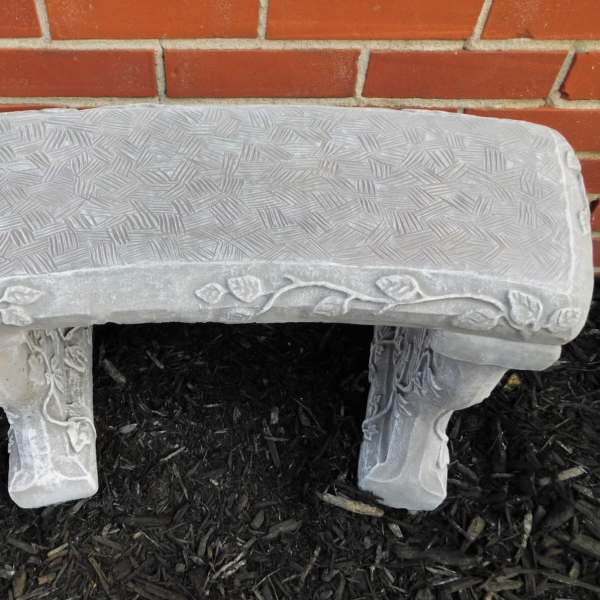 Decorative stone garden bench against a brick wall