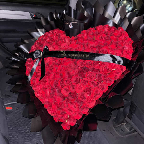 Heart-shaped bouquet of red roses wrapped in black paper with a black ribbon
