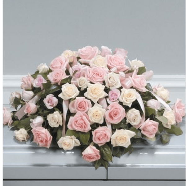 Casket spray of pink and white roses with ribbon accents