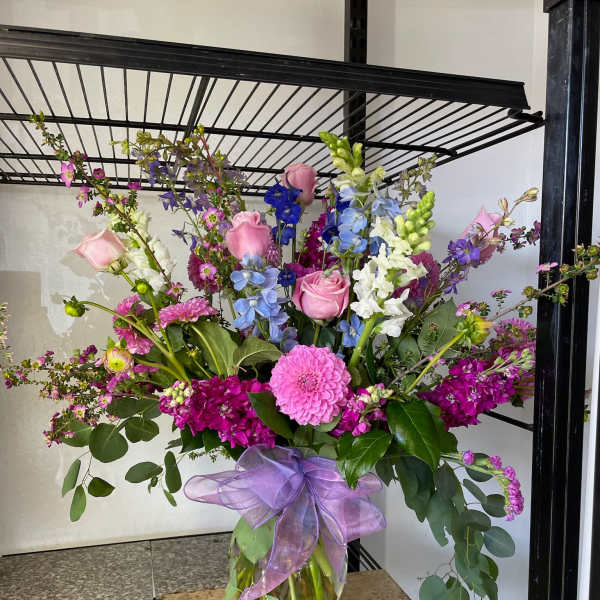 Large mixed bouquet in a glass vase with pink, purple, blue, and white flowers