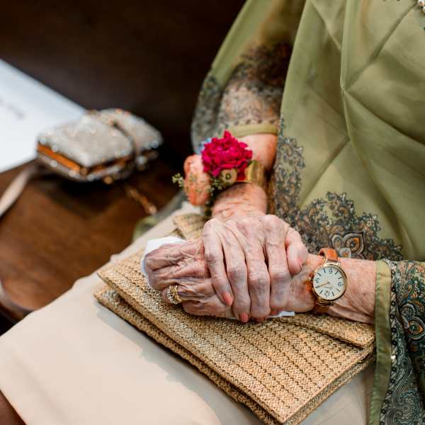 Elderly woman wearing a pink flower corsage and holding a woven clutch