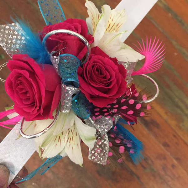 Handheld bouquet of hot pink roses and white lilies with colorful decorative feathers