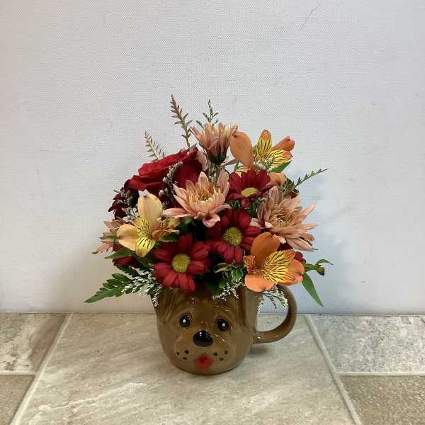 Mixed bouquet in a brown bear mug with red, peach, and yellow flowers
