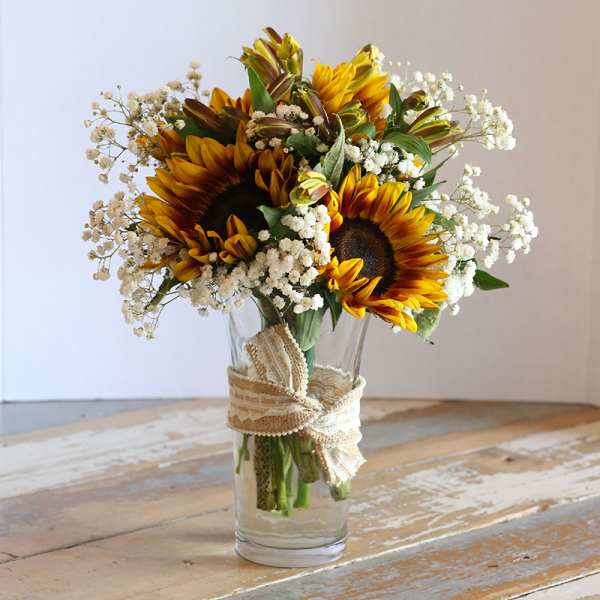 Sunflower bouquet in a clear glass vase with white baby's breath