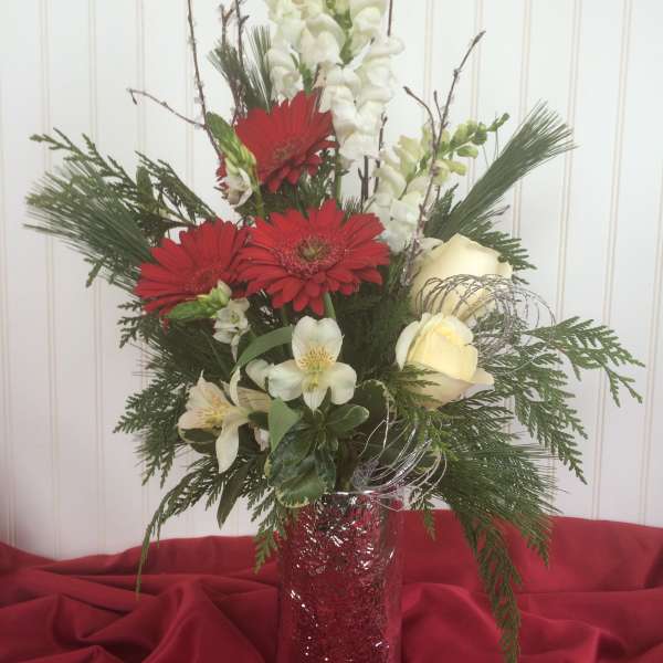 Tall floral arrangement with red gerbera daisies, white blooms, and a red vase