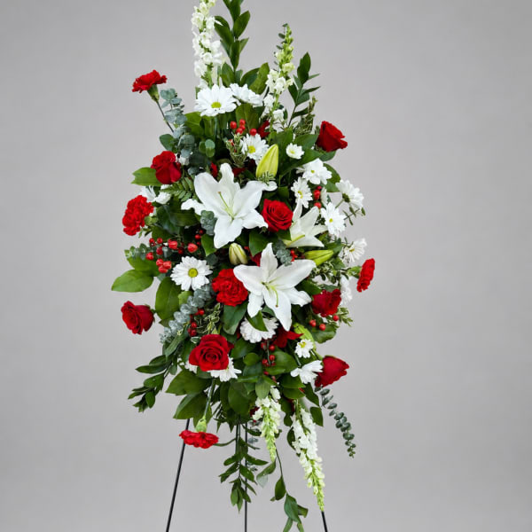 Tall standing floral spray with red roses and white lilies on a black easel