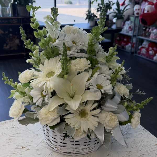 White floral basket arrangement with daisies, lilies, and carnations