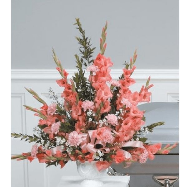 Tall pink floral arrangement in a white vase with a satin ribbon