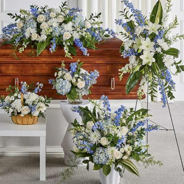 Blue and white floral funeral arrangements around a wooden casket