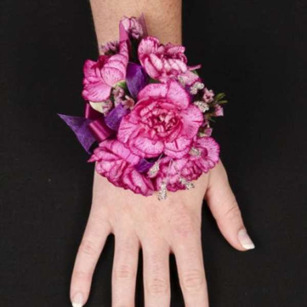 Pink floral wrist corsage on a person's hand