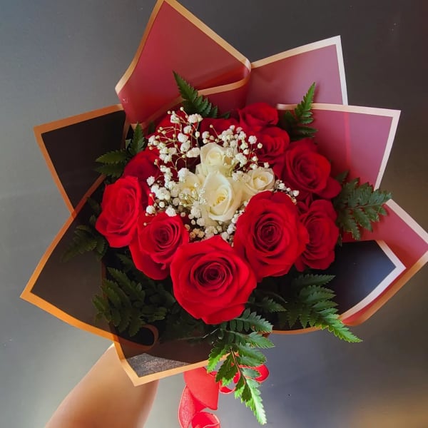 Bouquet of red and white roses wrapped in dark paper
