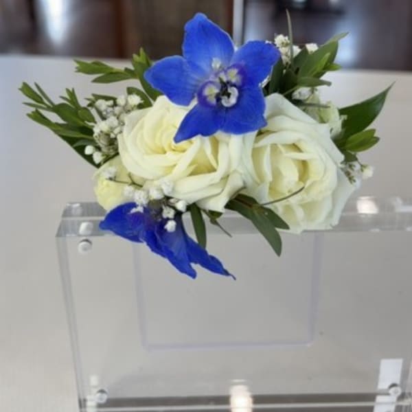 White roses with blue orchids in a clear acrylic holder