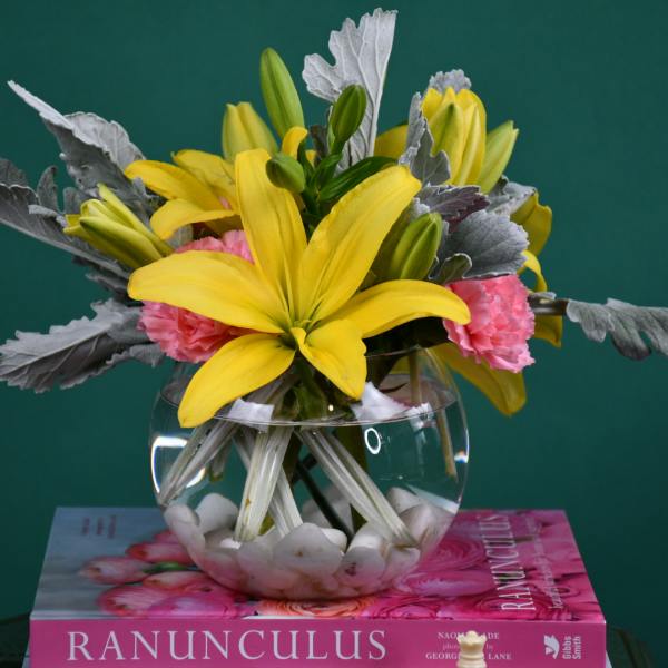 Yellow lilies and pink carnations in a clear glass bowl vase