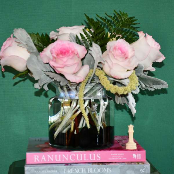 Pink and white roses in a glass vase with greenery