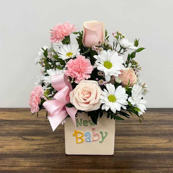 Pink and white flower arrangement in a New Baby container