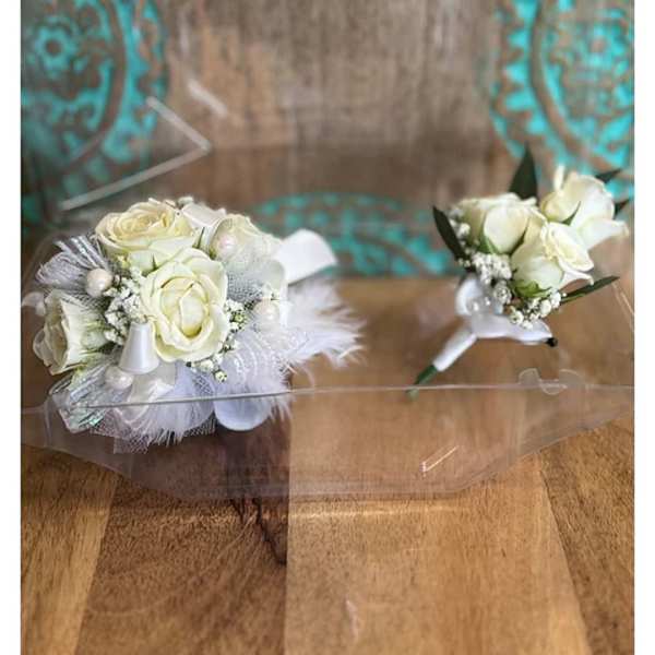 Two small white rose boutonnieres with feather accents