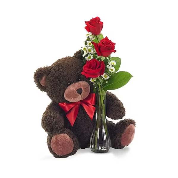 Teddy bear holding red roses in a glass vase