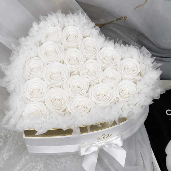 Round bouquet of white roses wrapped in sheer white tulle