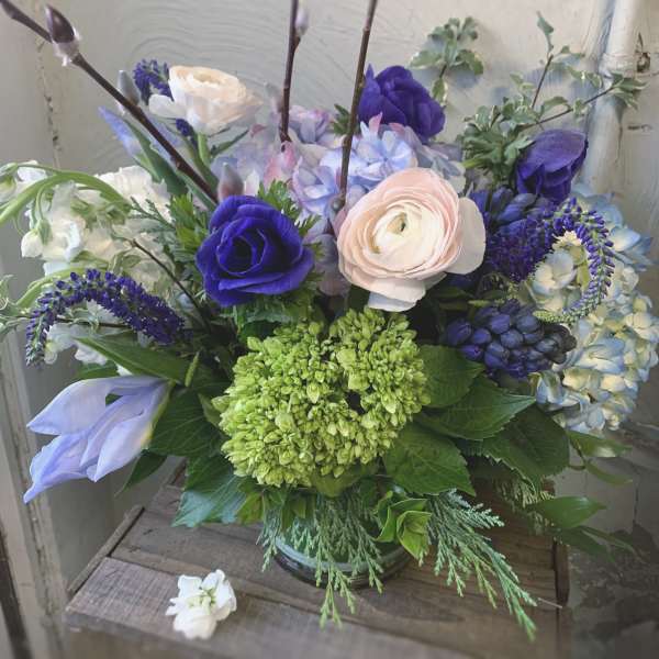 Bouquet of purple, blue, and blush flowers in a glass vase