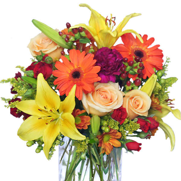 Mixed bouquet of lilies, roses, and gerbera daisies in a clear glass vase