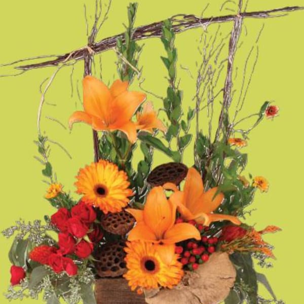 Orange lilies and gerbera daisies with red roses in a rustic basket