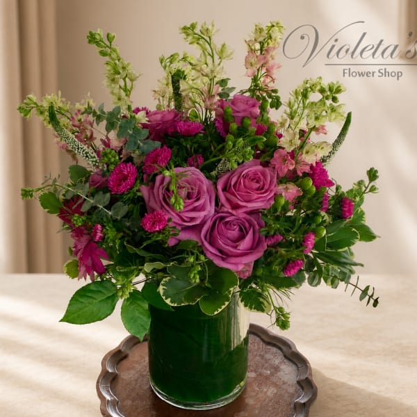 Pink and purple roses with mixed flowers in a glass vase