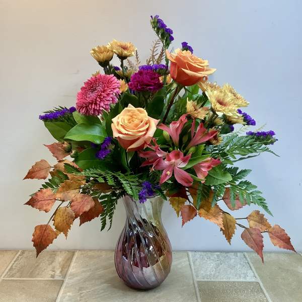 Mixed bouquet of roses, chrysanthemums, and alstroemeria in a glass vase
