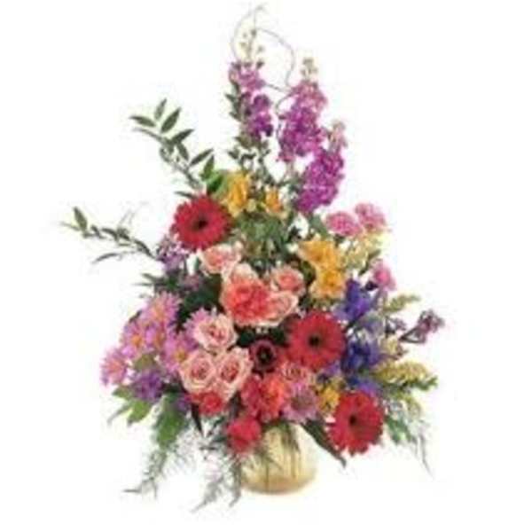 Tall mixed flower arrangement in a gold vase with red and purple blooms