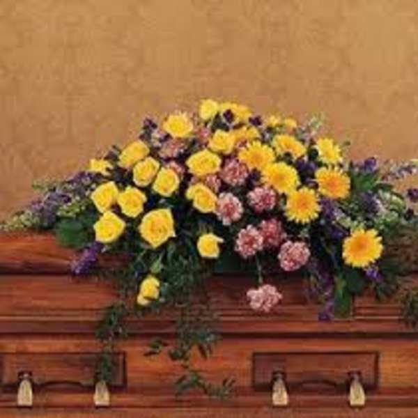 Yellow and pink floral arrangement on a wooden casket