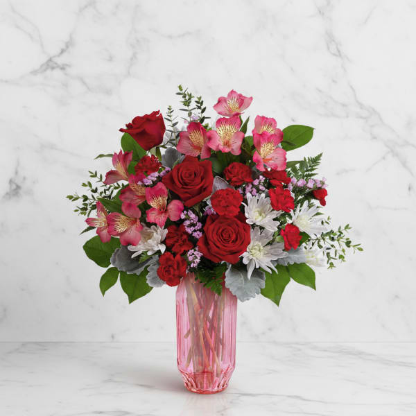 Red and pink mixed bouquet in a pink glass vase