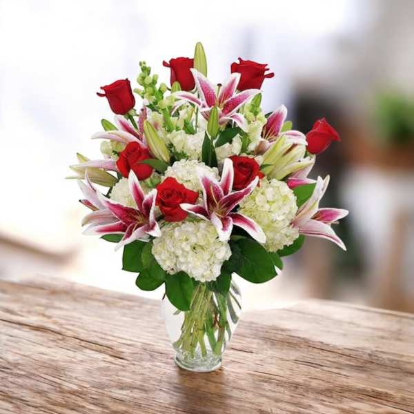 Bouquet of red roses and pink lilies in a clear glass vase