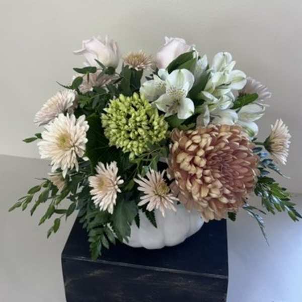 White and pale pink flowers arranged in a white pumpkin-shaped container