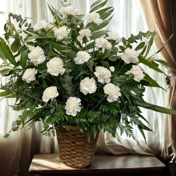 White carnations in a woven basket with mixed greenery