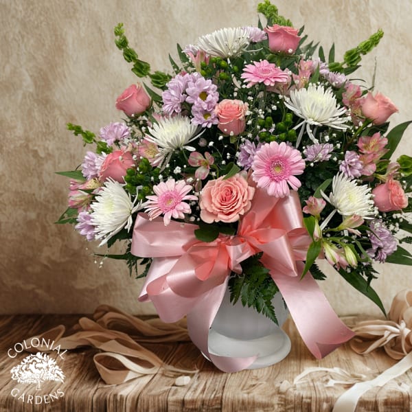 Pink and white mixed bouquet in a white vase with a satin ribbon