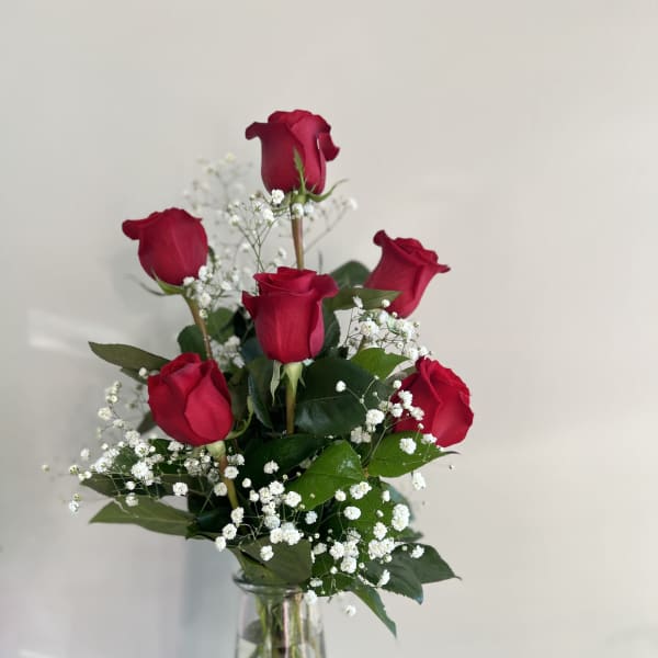 Red roses arranged in a clear glass vase with white baby's breath