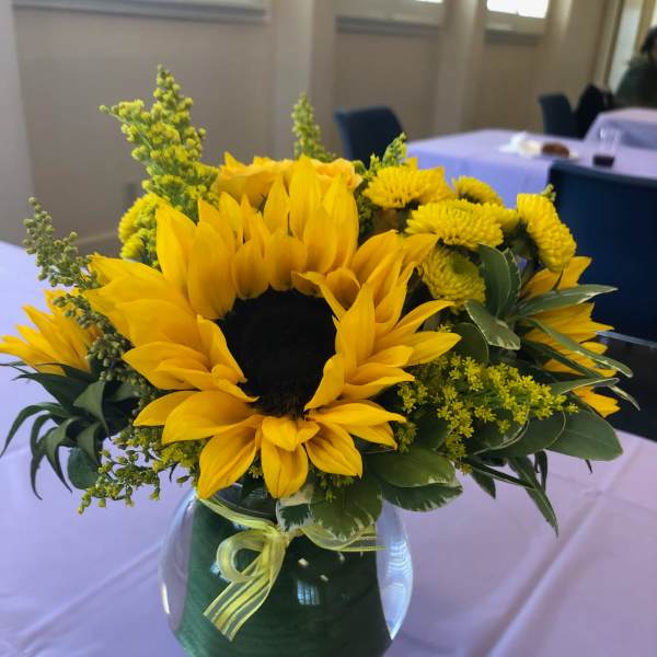 Yellow sunflower arrangement in a glass vase with a ribbon